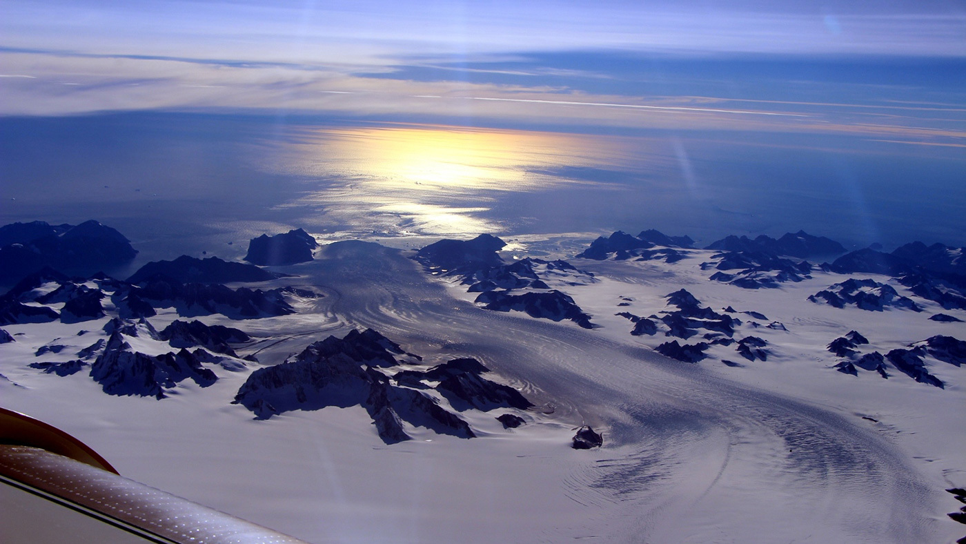 Greenland's Steenstrup Glacier, with the midmorning sun glinting off the Denmark Strait in the background. The image was taken during a NASA IceBridge airborne survey of the region in 2016. Credit: NASA/Operation IceBridge › Larger view